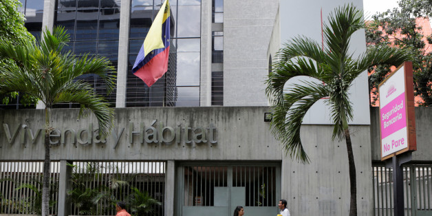 People walk past the closed entrance of the National Bank of Housing and Habitat building in Caracas, Venezuela, April 28, 2016. REUTERS/Marco Bello