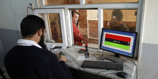 A border official checks passports at the Ras Jdir border, between Libya and Tunisia, 175 km west of Tripoli December 15, 2014. Libya's recognised government conducted air strikes against rival government forces trying to seize major oil ports in the east and against targets in the west on Monday, witnesses said. An air strike targeted the town of Zuwara near the border to Tunisia, witnesses said. But the rival government kept control of the main crossing in Ras Jdir. Picture taken December 15, 2014. REUTERS/Ismail Zitouny (LIBYA - Tags: POLITICS CIVIL UNREST)