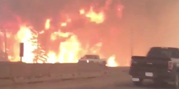 This photo provided by Tyler Burgett shows flames from a wildfire along Highway 63 in Fort McMurray, Alberta, Tuesday, May 3, 2016. At least half of the northern Alberta city was ordered evacuated Tuesday as a wildfire whipped by winds engulfed homes and sent ash raining down on residents. (Tyler Burgett via AP) MANDATORY CREDIT