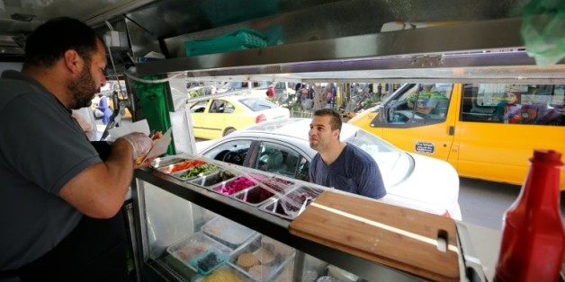 Khaldoun al-Barghouthi, co-propriétaire du food-truck "Food Train" sert un client à Ramallah, dans les Territoires palestiniens, le 3 mai 2016