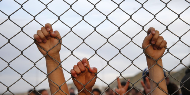 Syrian refugee children chant slogans behind a fence at the Nizip refugee camp in Gaziantep province, southeastern Turkey, following a visit by German Chancellor Angela Merkel and top European Union officials, Saturday, April 23, 2016. Merkel and the officials, under pressure to reassess a migrant deportation deal with Turkey, were traveling close to Turkey's border with Syria on Saturday in a bid to bolster the troubled agreement. (AP Photo/Lefteris Pitarakis)