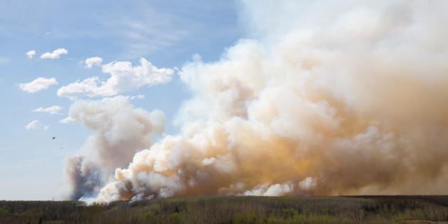 A helicopter flies past thick smoke while battling a major forest fire outside of Fort McMurray May 4, 2016. REUTERS/Topher Seguin TPX IMAGES OF THE DAY