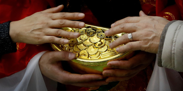 A man and a woman touch gold coins which are carried by a worker dressed as a God of Fortune at a shopping mall in Beijing, Friday, Feb. 12, 2016. Millions of Chinese are celebrating the Lunar New Year, which marks the Year of the Monkey on the Chinese zodiac. (AP Photo/Andy Wong)