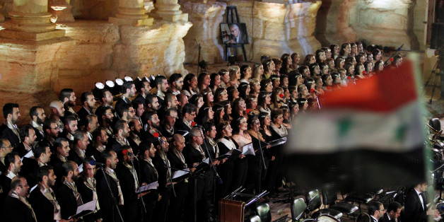 Al-Farah choir perform as a Syrian national flag flutters during a musical event called "Gate of the Sun" that was held to honour victims of the Syria's conflict in the amphitheater of the historic city of Palmyra, Syria May 6, 2016. REUTERS/Omar Sanadiki