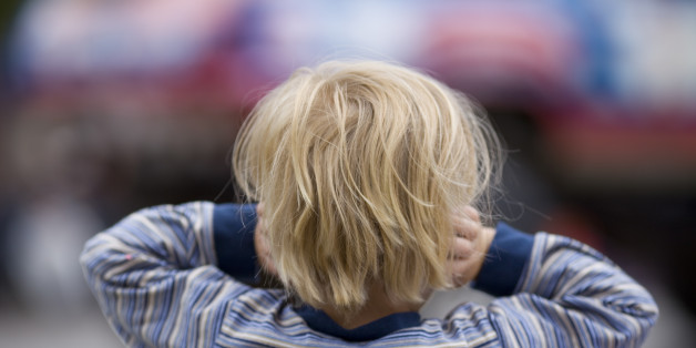 A little boy holds his ears.