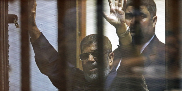 Deposed Egyptian President Mohamed Mursi greets his lawyers and people from behind bars after his verdict at a court on the outskirts of Cairo, Egypt June 16, 2015. An Egyptian court sentenced deposed President Mohamed Mursi to death on Tuesday on charges of killing, kidnapping and other offences during a 2011 mass jail break.The general guide of the Muslim Brotherhood, Mohamed Badie, and four other Brotherhood leaders were also handed the death penalty. More than 80 others were sentenced to dea