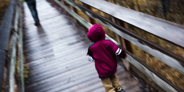 Little boy running after his mother on footbridge, blurred motion. Rock Creek, Montana.
