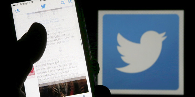 A man reads tweets on his phone in front of a displayed Twitter logo in Bordeaux, southwestern France, March 10, 2016. REUTERS/Regis Duvignau/Illustration/File Photo