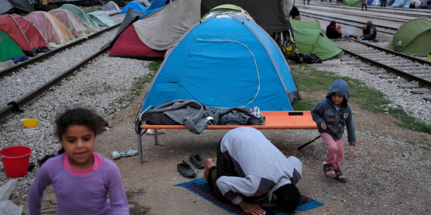 Children play as a man prays at a makeshift camp for migrants and refugees at the Greek-Macedonian border near the village of Idomeni, Greece, May 10, 2016. REUTERS/Marko Djurica
