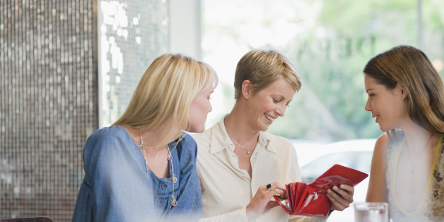 Woman sitting with her friends in a restaurant and looking into her wallet