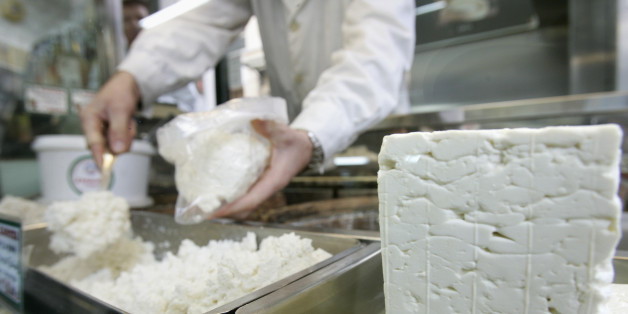 A cheesemonger puts pieces of Greece's trademark feta cheese in a bag for a customer in central Athens November 21, 2007. Greece has declared war on white cheeses, launching 2008 as the "Year of Feta" and hoping promotion of its classic salty cheese will win more international clients. REUTERS/John Kolesidis (GREECE)