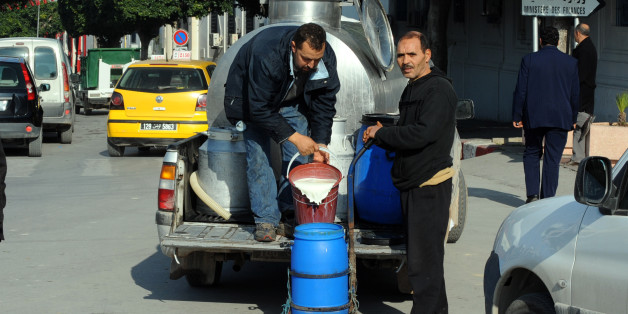 A man pours milk in a container for Tunisian citizens in the Kasbah street on January 17, 2011 in Tunis. Hundreds of people rallied in central Tunis on Monday to demand the abolition of ousted president Zine El Abidine Ben Ali's RCD party as police fired volleys of tear gas to break up the protest. AFP PHOTO / FETHI BELAID (Photo credit should read FETHI BELAID/AFP/Getty Images)