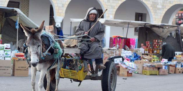 A Berber man dressed in traditional clothes rides a donkey-pulled-cart in the market of the town of Ben Guerdane, some 40 kilometres west of the Libyan border, on February 6, 2016.Tunisia on February 6, 2016 completed the construction of a barrier along its border with Libya, months after attacks on its national museum and a beach resort that killed dozens of tourists. Defence Minister Farhat Horchani told reporters that the construction of berms and water-filled trenches marks 'an important day