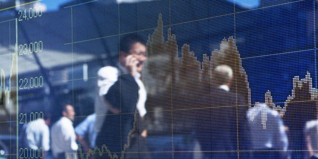A silhouette of business man talking on smart phone and walking on the road is reflected on the display of the stock price chart in the business district.