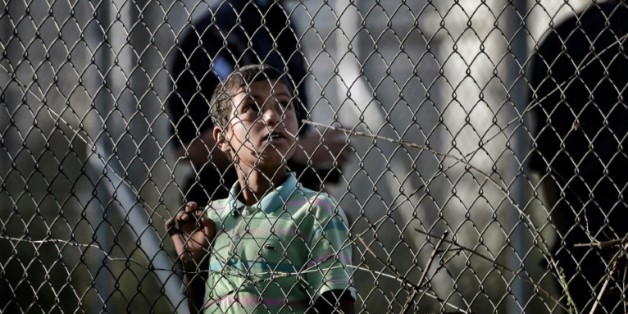 Un enfant regarde à travers les grillages du centre de détention de migrants de Moria à Mytilène en Grèce le 15 avril 2016