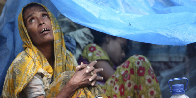 FILE - In this July, 28, 2009 file photo, a Bangladeshi woman looks skyward from inside her temporary home, a tent set up on the roadside, in Dhaka, Bangladesh as heavy monsoon rains have battered Bangladesh's capital, flooding streets and homes, stranding thousands and forcing businesses and schools to close. Experts say Asia and the South Pacific, home to 4.3 billion people or 60 percent of all humankind, faces rising risks from climate change that threaten food security, public health and social order, in a report given Monday, March 31, 2014 by a United Nations scientific panel meant to guide policymakers and form the foundation for a new climate treaty due next year. (AP Photo/Pavel Rahman, File)
