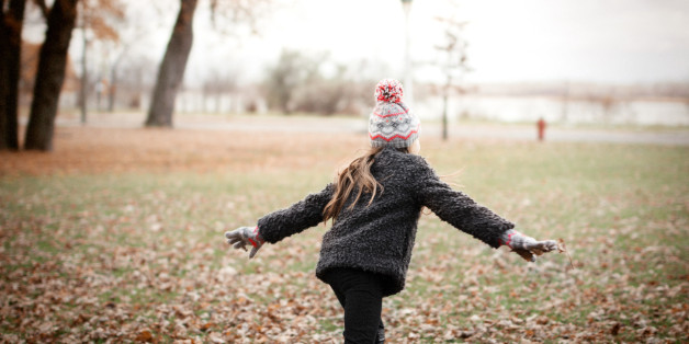 Adorable little girl with autumn leaves in the beauty park.