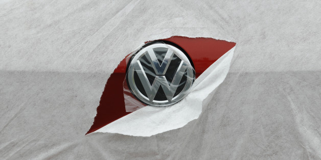 A VW badge is seen through torn wrapping as a Volkswagen Golf is delivered to a car dealership in Portslade near Brighton in southern England April 24, 2013. In the 12 months ending in March, car registrations in Britain rose 7.2 percent compared with the same period a year earlier. REUTERS/Luke MacGregor (BRITAIN - Tags: TRANSPORT BUSINESS)