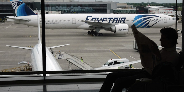 A passenger reads a newspaper at a departure hall of London's Heathrow terminal as an EgyptAir plane taxis on the tarmac of the airport May 20, 2016 REUTERS/Yannis Behrakis
