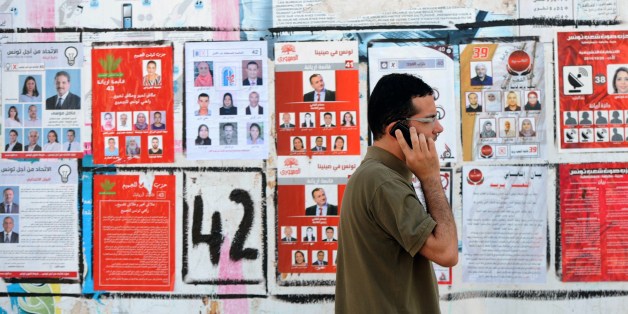 A Tunisian speaks on the phone as he walks past election posters put up on a street ahead of the parliamentary election in the Tunis suburb of Ariana on October 21, 2014. Tunisians vote on October 26, 2014 to elect their first parliament since the country's 2011 revolution, in a rare glimmer of hope for a region torn apart by post-Arab Spring violence and repression. AFP PHOTO / FETHI BELAID (Photo credit should read FETHI BELAID/AFP/Getty Images)
