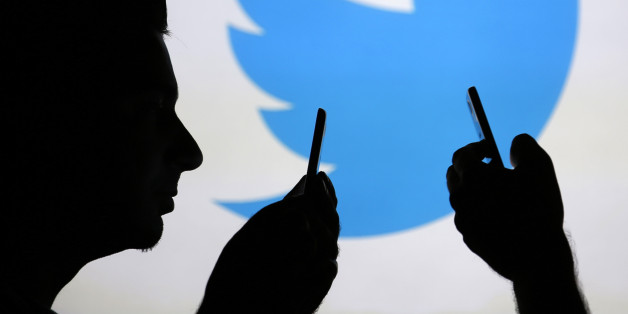 Men are silhouetted against a video screen with a Twitter logo as he poses with a Samsung S4 smartphone in this photo illustration taken in the central Bosnian town of Zenica, August 14, 2013. REUTERS/Dado Ruvic (BOSNIA AND HERZEGOVINA - Tags: BUSINESS TELECOMS)
