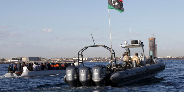 Libyan coast guards (R) escort migrants, who tried to flee to Europe, after the migrants were stopped by the coast guards and made to head to Tripoli September 29, 2015. The North African country has turned into a major hub for human traffickers smuggling African migrants by boat to Italy, with the Libyan coastguard under pressure from Europe to stem the flow. REUTERS/Ismail Zitouny