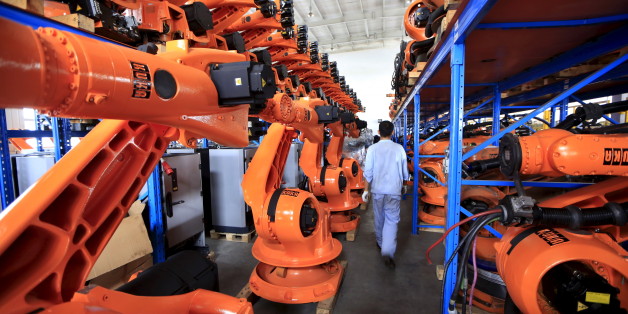 A worker walks past second-hand robots in a factory in Shanghai, August 21, 2015. More than a hundred second-hand robots used to make Audi A3s at a German car factory are going through refurbishment at a Wecan Group factory in Shanghai. Picture taken August 21, 2015. REUTERS/Aly Song