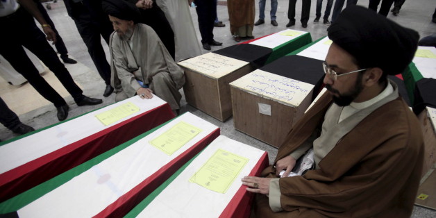 Clerics pray next to coffins of victims of Friday's bombing at the Imam Sadeq mosque in Kuwait City, at the international airport in Najaf, south of Baghdad, June 27, 2015. The attack, which killed 27 and injured more than 200 at the mosque, was claimed by Islamic State's Wilayat of Najd division. Some of victims' bodies have been brought to the Shi'ite holy cities of Najaf and Karbala in Iraq for burial. The coffins are seen shrouded with Kuwaiti flags. REUTERS/Alaa Al-Marjani