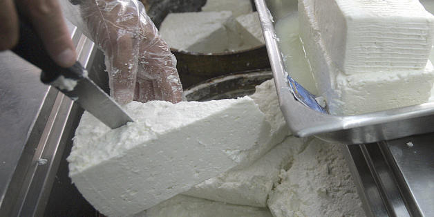 Athens, GREECE: A shop assistant lifts a slab of feta cheese in Athens, Greece, 25 October 2005. The Greek agriculture ministry 25 October welcomed a ruling by the EU's highest court awarding Greece exclusive rights to the feta cheese brand over claims from producers elsewhere in Europe. AFP PHOTO/Aris Messinis (Photo credit should read ARIS MESSINIS/AFP/Getty Images)