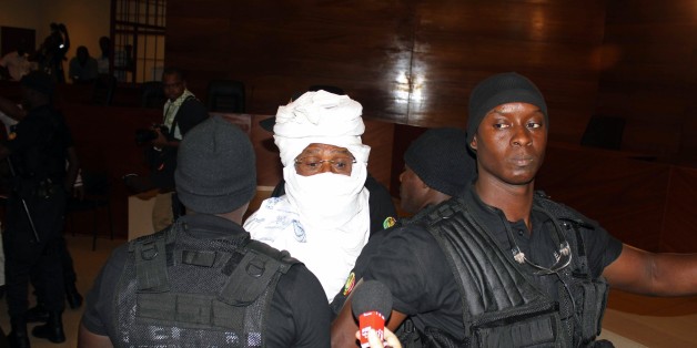 CORRECTS NAME OF PHOTOGRAPHER Security personnel surround former Chadian dictator Hissene Habre inside the court in Dakar, Senegal, Monday, July 20, 2015. The trial of former Chadian dictator Hissene Habre, accused of overseeing the deaths of thousands, had a chaotic beginning Monday as security forces ushered the ex-leader into and then out of the Senegal courtroom amid protests by his supporters.(AP Photo/Ibrahima Ndiaye)