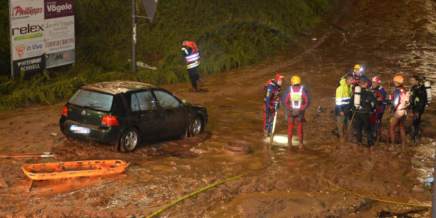 Feuerwehrmänner und Rettungstaucher stehen um den Gullischacht, in dem zwei Menschen starben