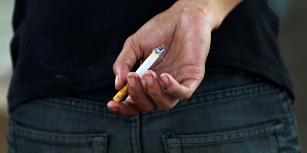 An Indonesian youth holds a cigarette while waiting for a train in Jakarta May 24, 2012. REUTERS/Beawiharta/File Photo