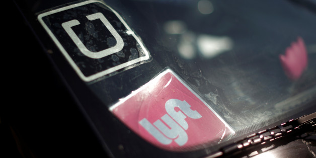 A driver displays Uber and Lyft ride sharing signs in his car windscreen in Santa Monica, California, U.S., May 23, 2016. A flurry of deals between big automakers and ride sharing and transportation startups is rewriting the playbook in the contest to control the future of personal transportation. REUTERS/Lucy Nicholson/Files