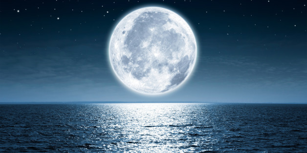 Full moon rising over empty ocean at night with copy space