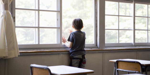 Boy (6-7) looking out of classroom window, rear view