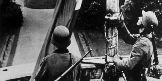 circa 1940: German troops hoisting the Nazi flag on the Royal Castle at Laeken, near Brussels, after their invasion. (Photo by Keystone/Getty Images)