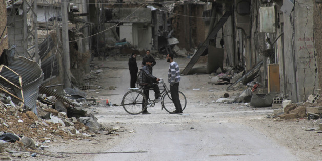 Men chat near buildings damaged by what activists said was shelling by forces loyal to Syria's President Bashar al-Assad in Daraya, near Damascus February 2, 2014. Picture taken February 2, 2014.REUTERS/Omar Abu Bakr (SYRIA - Tags: POLITICS CIVIL UNREST CONFLICT)
