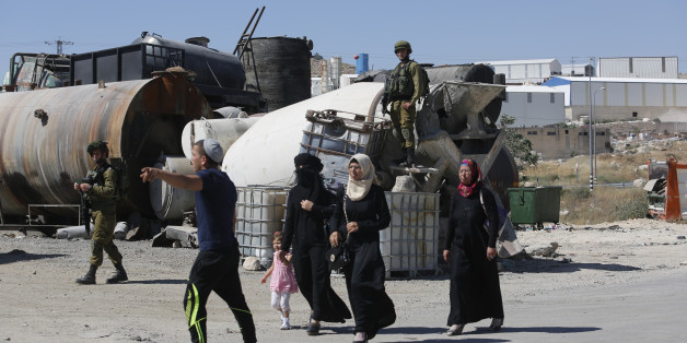 Israeli soldiers prevent Palestinian residents from crossing a security checkpoint at the closed entrance of the West Bank village of Yatta, near Hebron, Thursday, June 9, 2016. Israel on Thursday imposed a series of sweeping restrictions on Palestinian movement and deployed hundreds of additional troops to the West Bank in response to a Tel Aviv attack that killed four Israelis. Israeli police said the two gunmen in their twenties were members of the same family from the Palestinian village of Yatta, one gunman was wounded and was being treated in custody in an Israeli hospital. The other was apprehended by security guards at the scene. (AP Photo/Nasser Shiyoukhi)