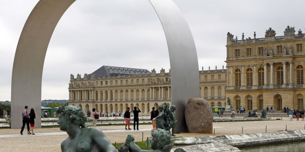Visitors walk under The Arch of Versailles, a work of art by Korean artist Lee Ufan, displayed in the gardens of the Versailles Castle, west of Paris, Thursday June 19, 2014. Korean painter and sculptor Lee Ufan is this summerâs guest artist in Versailles. Ten new works have been placed throughout the palace and gardens. The exhibition lasts until Nov. 2014. (AP Photo/Remy de la Mauviniere)