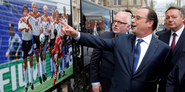French President Francois Hollande (2ndL), flanked with French Soccer specialist Pierre Louis Basse (L), comment on a photo of Bulgarian soccer player Hristo Stoitchkov shooting a free kick against Germany in 1994 Euro quarter final during a visit of an exhibition entitled "Football de Legendes, une Histoire Europeenne" ('Soccer Legends, a European history'), outside Paris City Hall, in Paris, France, May 9, 2016. REUTERS/Francois Mori/Pool