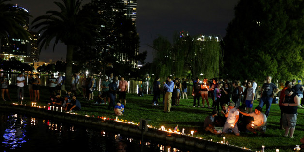 People sit by the water with candles during a vigil in a park following a mass shooting at the Pulse gay nightclub in Orlando, Florida, U.S. June 12, 2016. REUTERS/Carlo Allegri