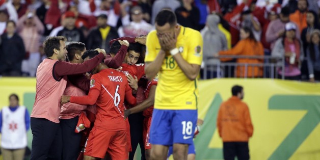 The Peru team celebrates their 1-0 victory as Brazil's Renato Augusto (18) leaves the pitch after a Copa America Group B soccer match between Brazil and Peru Sunday, June 12, 2016, in Foxborough, Mass. (AP Photo/Steven Senne)