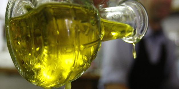 A diner pours olive oil on a salad at a restaurant in Rome May 17, 2007. When you buy a bottle of olive oil, the rolling Tuscan hills on the label and the "made in Italy" stamp should reassure you the product is as Italian as Chianti or Armani. In fact, there is no guarantee the oil is from Italy. That would change under a bill that forces manufacturers to declare where their oil comes from, meaning many famous brands would have to reveal, for the first time, that most of their "Italian" oil is