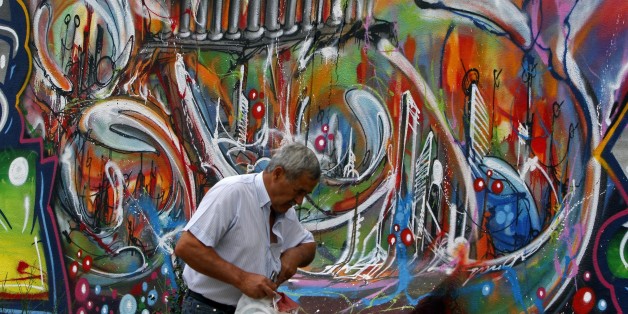 A man walks past a graffiti depicting the economic situation in Europe, in Lisbon August 22, 2011. Turbulent markets threaten to derail the plans of cash-strapped European governments to sell off state assets, with those who can afford to wait likely to delay and those who cannot busy exploring other ways to raise the money. Tumbling equity prices have wiped billions of dollars off the value of state-owned companies since the start of the month, clouding the outlook for planned sales by countrie
