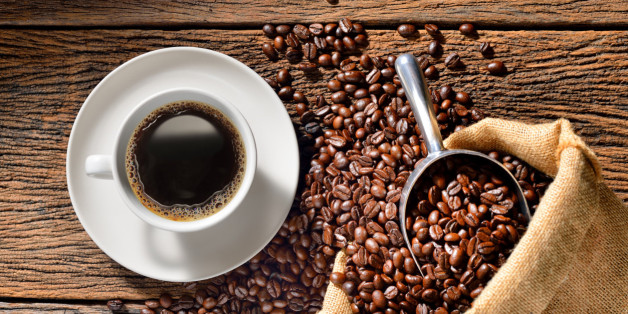 Cup of coffee and coffee beans on wooden table