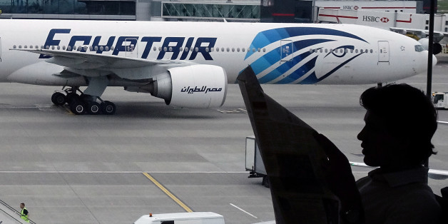 FILE PHOTO - A passenger reads a newspaper at a departure hall of London's Heathrow terminal as an EgyptAir plane taxis on the tarmac of the airport May 20, 2016. REUTERS/Yannis Behrakis/File Photo