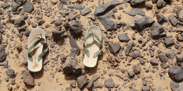 A pair of flip flops, which were left behind by a migrant, lie on the ground in the desert near the border between Algeria and Libya May 29, 2014. Libya's southwestern tip in the Sahara bordering Algeria and Niger has turned into an open door for illegal migrants from sub-Saharan countries heading for Europe, with the chaotic government in Tripoli appearing to have abandoned all control. The revolt that overthrew Libyan leader Muammar Gaddafi three years ago emptied Libya's arsenals, flooded the