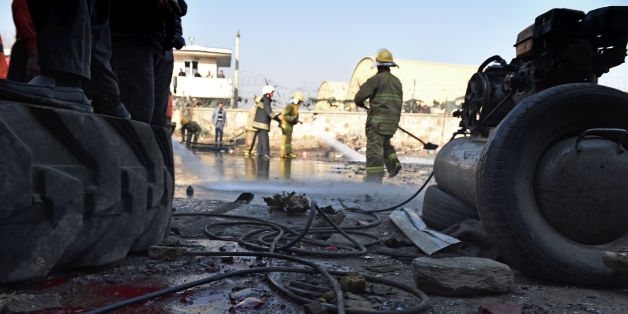 TOPSHOT - Afghan firefighters wash a road at the site of a suicide car bomb near the international airport in Kabul on December 28, 2015. A Taliban bomber has detonated an explosives-packed vehicle near Kabul airport in an attack on a NATO convoy, killing one civilian a day after Pakistan's army chief visited the Afghan capital in an effort to revive peace talks.Four other civilians were wounded in the early morning attack, which comes amid a worsening security situation in Afghanistan as the Ta