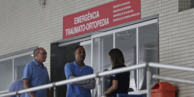 Employees stand in front an emergency entrance at the Souza Aguiar Hospital, in Rio de Janeiro, Brazil, Sunday, June 19, 2016. Brazilian police say armed men stormed the Rio de Janeiro hospital to free a suspected drug trafficker, sparking a shootout with officers, with at least one patient killed, and a nurse and an off-duty policeman wounded. (AP Photo/Silvia Izquierdo)