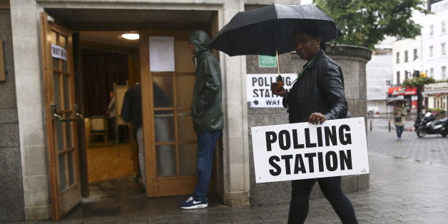 A woman carries an umbrella and a polling station sign at a polling station for the Referendum on the European Union in north London, Britain, June 23, 2016. REUTERS/Neil Hall